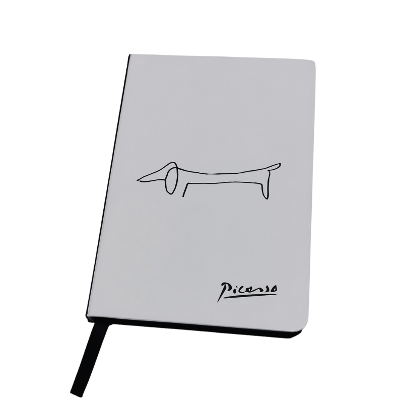 Ein weißes Notizbuch mit einem minimalistischen schwarzen Dackel-Motiv, inspiriert von Picasso, und Picasso’s Signatur in der Ecke.