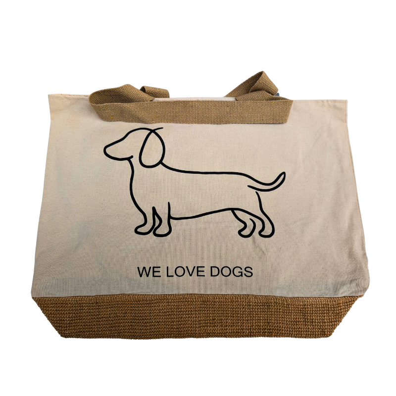 Naturfarbene Stofftasche mit braunem Juteboden, schwarzem Dackel-Umriss und dem Schriftzug „WE LOVE DOGS“ auf der Vorderseite.