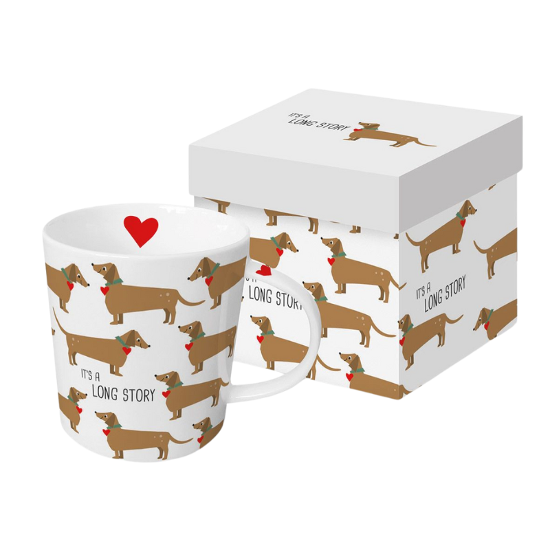 Weißer Keramikbecher bedruckt mit mehreren Dackeln, die Schleifen tragen und den Text ‘It’s a long story’ tragen, verpackt in einer weißen Geschenkbox mit einem roten Herz auf dem Becher.
