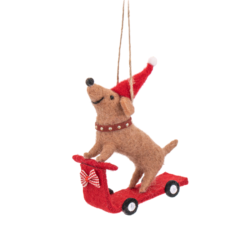 Weihnachtlicher Filzanhänger eines Dackels mit roter Mütze auf einem roten Roller mit Schleife.