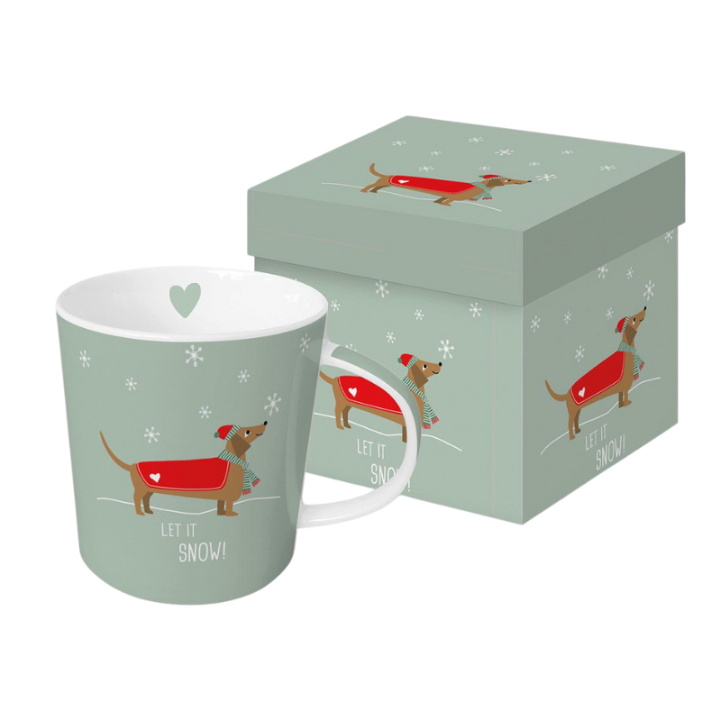 Hellgrüne Porzellantasse mit Weihnachtsmotiv eines Dackels im roten Mantel, Mütze und Schal, umgeben von Schneeflocken und dem Schriftzug „Let it Snow!“, inklusive passender Geschenkverpackung mit gleichem Design.