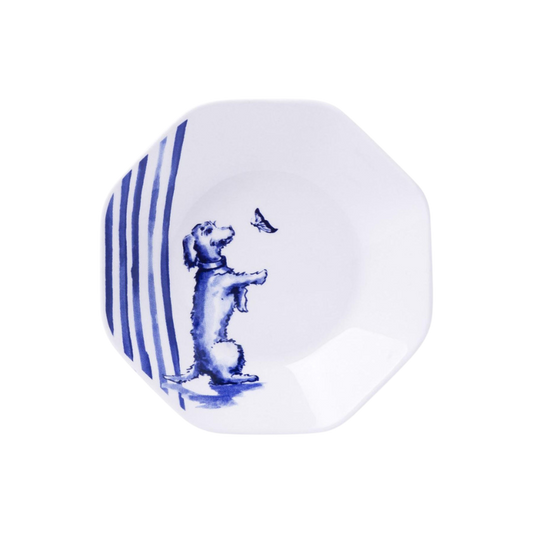 Weiße, sechseckige Teebeutelablage mit einem blau gezeichneten Dackel, der aufrecht sitzt und auf einen fliegenden Schmetterling schaut, umgeben von blauen Streifen am Rand.