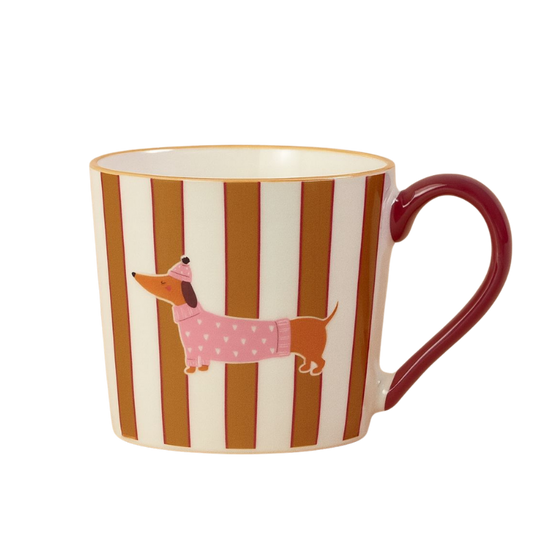 Keramiktasse mit vertikalen rot-braunen Streifen und einem Aufdruck eines Dackels im rosa Pullover und Mütze; roter Henkel.