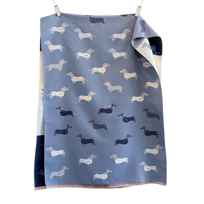 Wendeschal mit Dackel-Muster in zwei Farbvarianten – Blau und Beige – mit liebevollen Dackelmotiven, weich und kuschelig, ideal für Herbst und Winter.