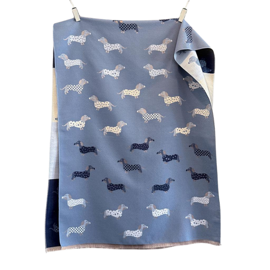 Wendeschal mit Dackel-Muster in zwei Farbvarianten – Blau und Beige – mit liebevollen Dackelmotiven, weich und kuschelig, ideal für Herbst und Winter.