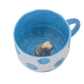Keramiktasse mit blauer Innenlasur, großen blauen Punkten außen und einer kleinen Dackel-Figur am Tassenboden.