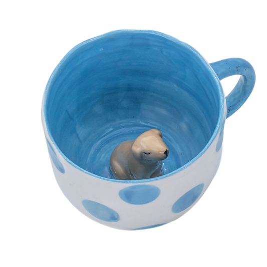 Keramiktasse mit blauer Innenlasur, großen blauen Punkten außen und einer kleinen Dackel-Figur am Tassenboden.