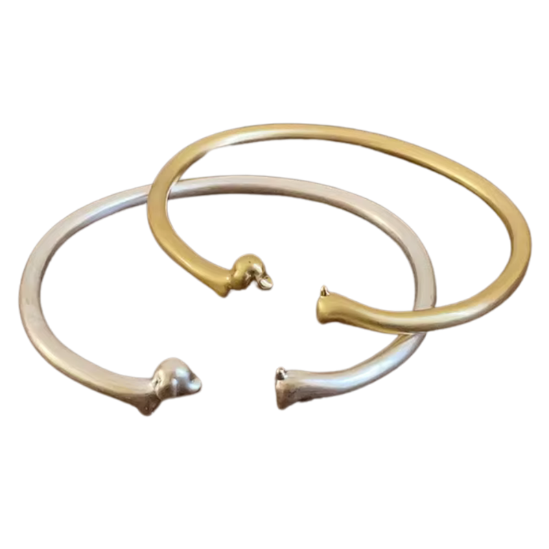 Zwei offene Armreifen in Gold und Silber mit Dackelkopf und -schwanz als Enden