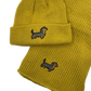 Gelbes Strick-Set bestehend aus Mütze und Schal, beide mit aufgesticktem Dackel-Motiv.