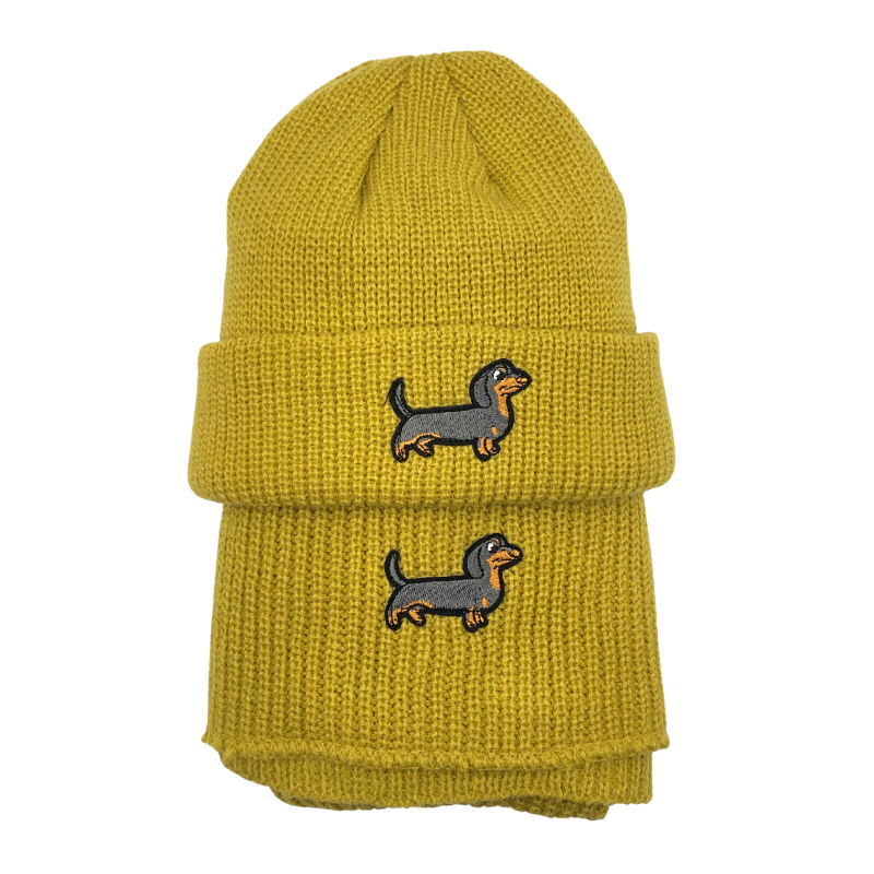Gelbes Strick-Set bestehend aus Mütze und Schal, beide mit aufgesticktem Dackel-Motiv.