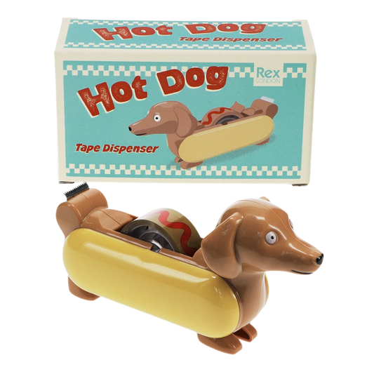 Lustiger Klebebandabroller in Form eines Dackels als Hot Dog mit gelbem Brötchen und rotem Senfdesign auf dem Rücken. Der Abroller wird in einer farbenfrohen Retro-Verpackung mit der Aufschrift “Hot Dog – Tape Dispenser” von Rex London geliefert.