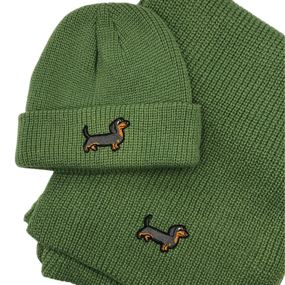 Grünes Strick-Set bestehend aus Mütze und Schal, verziert mit einem gestickten Dackel-Motiv.