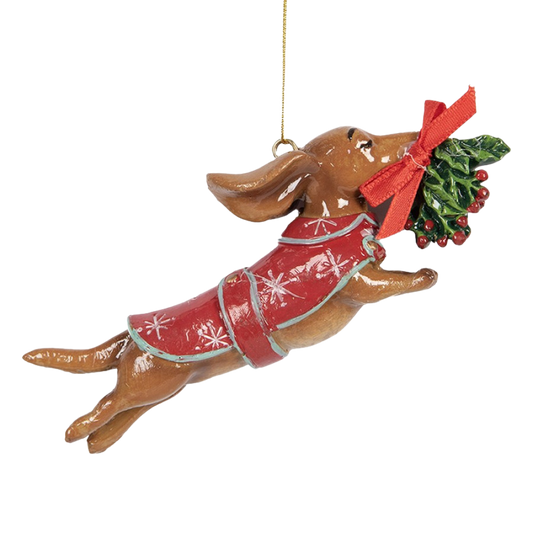 Weihnachtsanhänger eines fliegenden Dackels mit rotem Mantel und Mistelzweig im Maul.