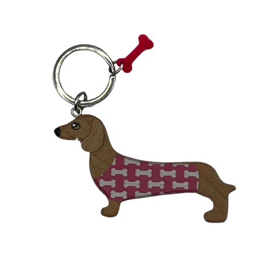 Holz-Schlüsselanhänger in Form eines Dackels mit bordeauxfarbenem Pullover mit weißen Knochenmotiven und pinkem Knochen-Anhänger am Schlüsselring.