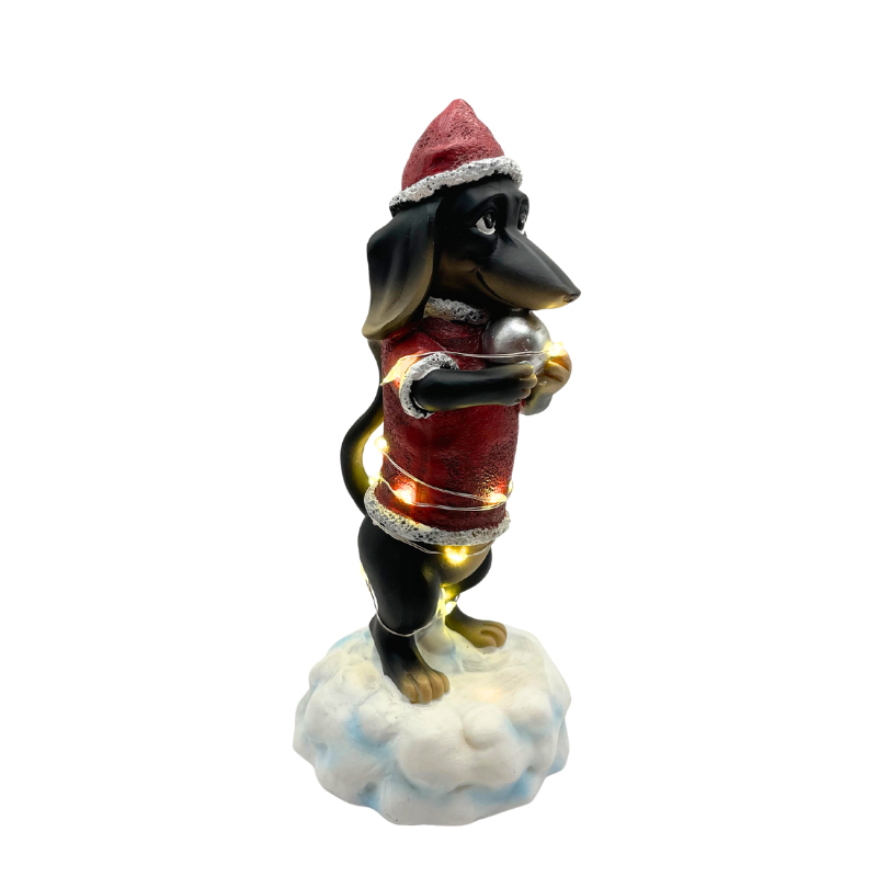 Weihnachtsdeko-Figur eines Dackels im roten Weihnachtsmann-Outfit mit Lichterkette und Geschenk in der Pfote.