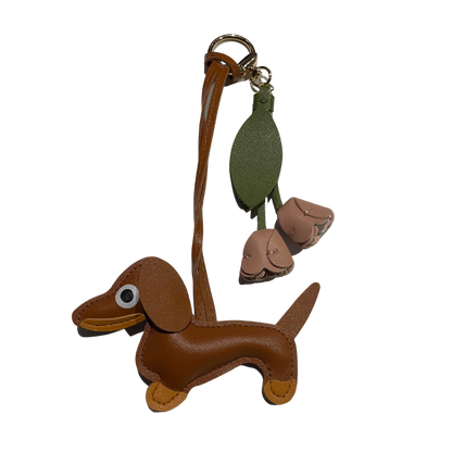 Brauner Dackel-Schlüsselanhänger aus Kunstleder mit zwei beigen Lederblüten und grünem Blattanhänger