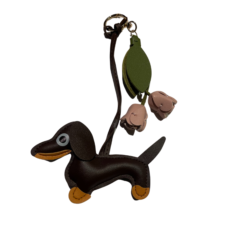 Schwarzer Dackel-Schlüsselanhänger aus Kunstleder mit zwei beigen Lederblüten und grünem Blattanhänger