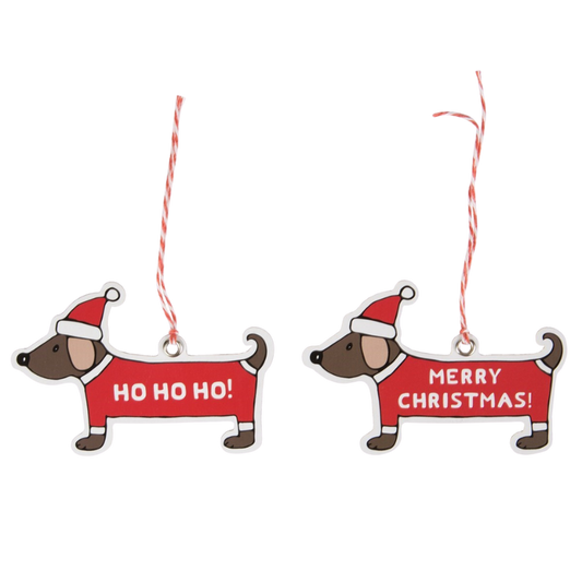 Zwei weihnachtliche Deko-Anhänger aus Holz in Form von Dackeln mit Nikolausmütze; einer trägt den Schriftzug „HO HO HO!“, der andere „MERRY CHRISTMAS!“, beide mit rot-weißem Bändchen zum Aufhängen.